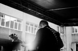 Monochrome image of a musician playing guitar on stage, showcasing the artistic vibe.