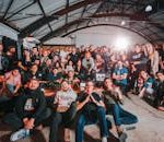 A happy and diverse group posing together in a São Paulo warehouse setting.